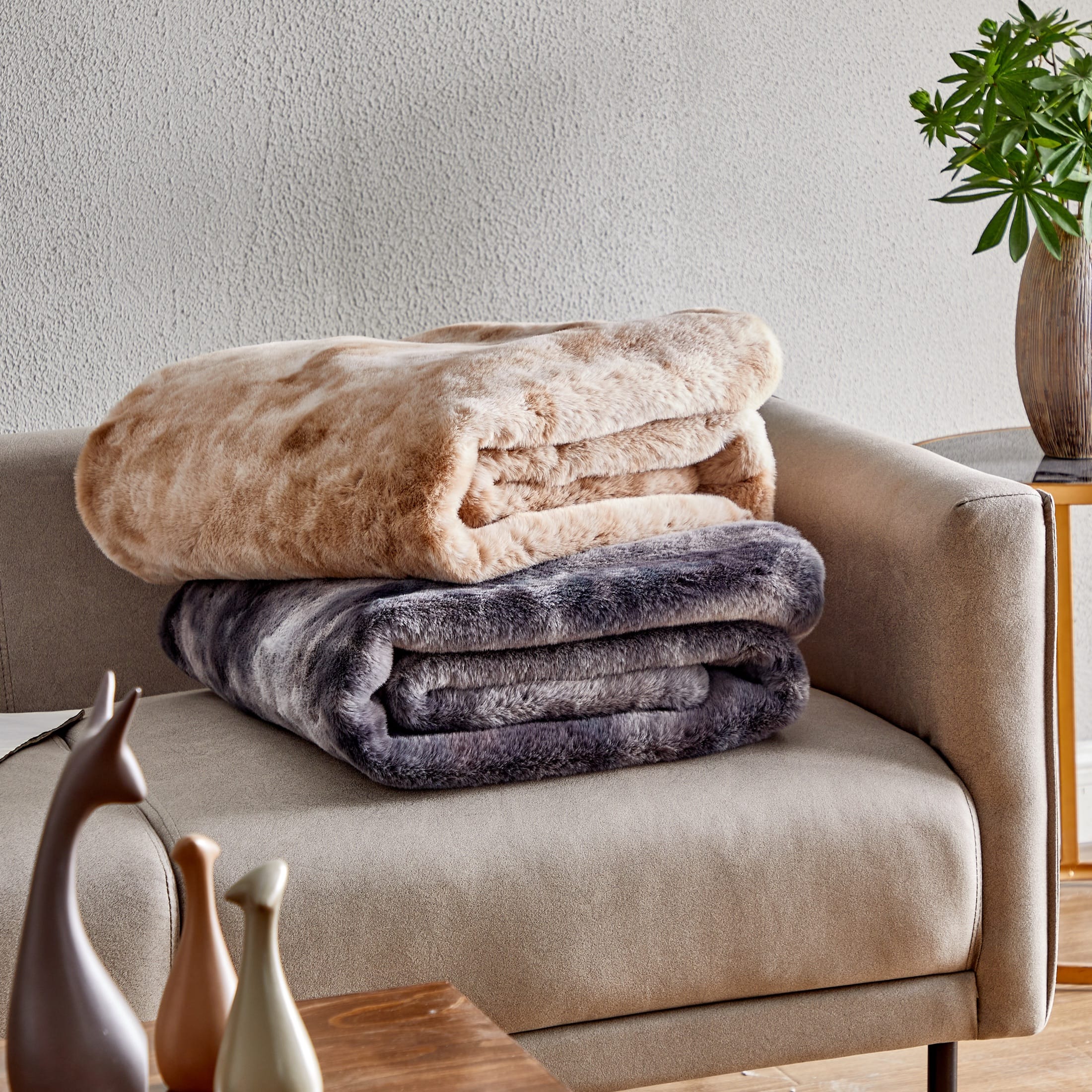 Two plush throw blankets folded on a chair