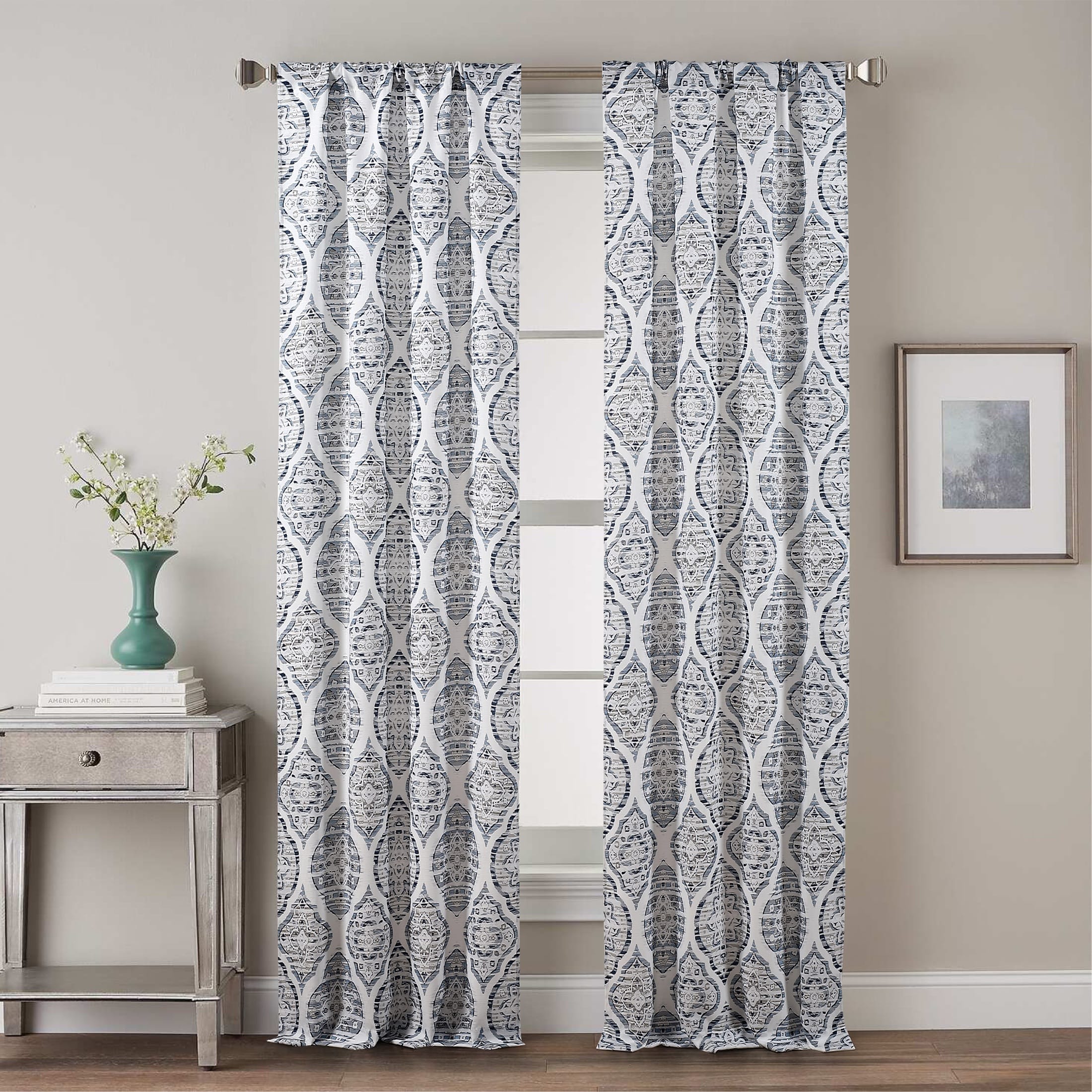 Blue patterned curtain panels photographed full-length with rod and room styling